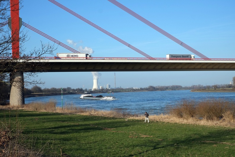 Im ersten Moment wirkt das Foto ruhig und statisch. Aber überall ist Bewegung. Das Wesen der Zeit, überall ist etwas in Bewegung. Das Kraftwerk im Hintergrund lässt Wasserdampf ab. Auf der Brücke ist der Güterverkehr präsent, auf dem Rhein ein Schiff. Auf der Auenwiese führt ein Mann seinen Hund aus. am_rheinufer.jpg
