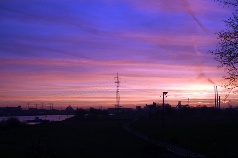 Die Straße zur Fähre morgens während die Sonne aufgeht. Der blaue Himmel ist schon da, die Sonne erreicht den Boden noch nicht. strasse_nach_walsum_am_morgen.jpg